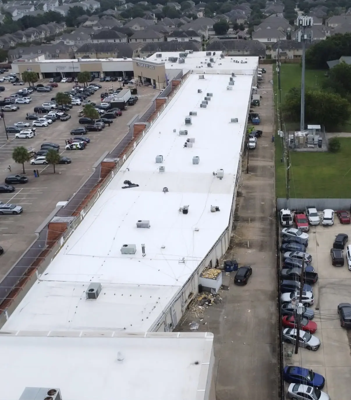 Aerial view of a long retail center with a new white TPO roof